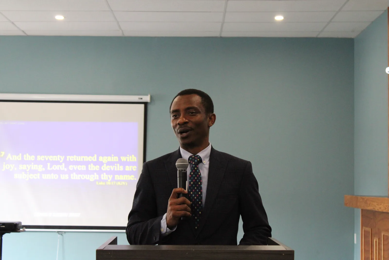 Pastor preaching from the pulpit with scripture on screen